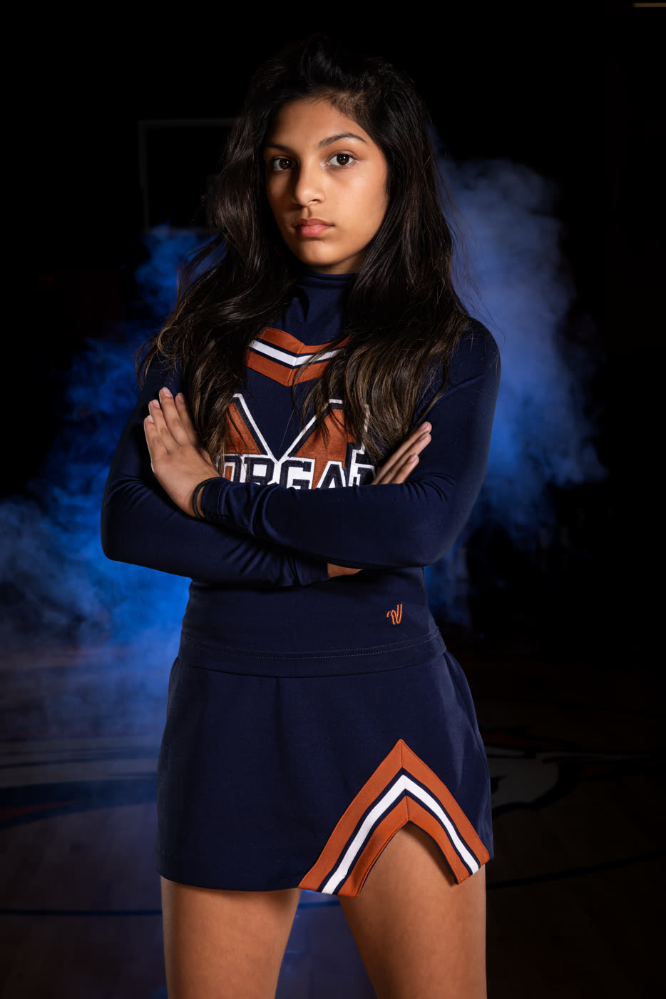 High school cheerleader portrait lit with dramatic colored lighting and haze, no composited background
